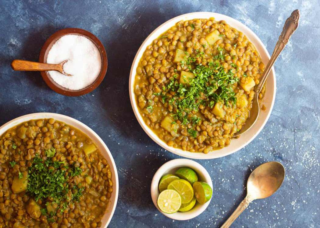 کاسه عدسی داغ روی میز چوبی